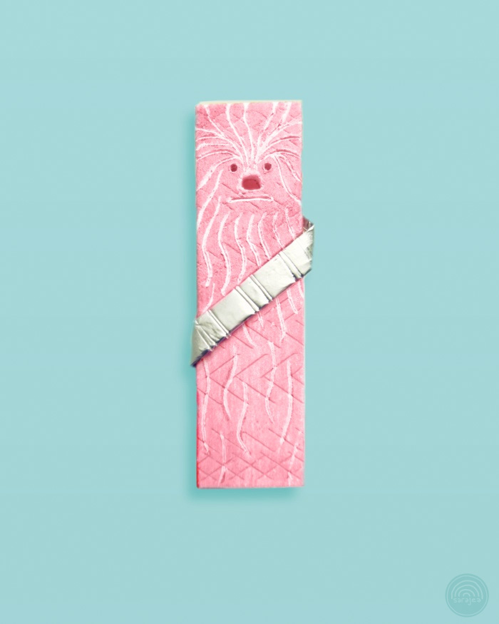 Photograph:  a stick of pink chewing gum modified to have fur and a wookiee-like face.  A metallic chewing gum wrapper has been fashioned into a cross-body bandolier.  It's cute.
